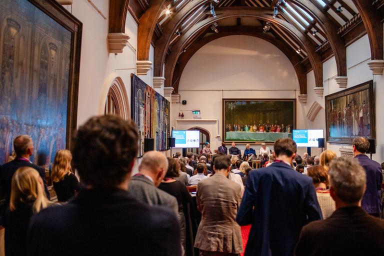 People standing and listening to a panel discussion