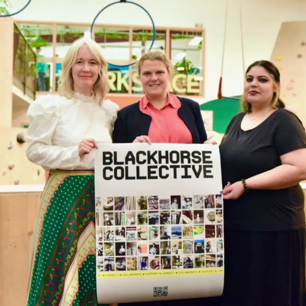 three people standing behind a blackhorse collective sign. 